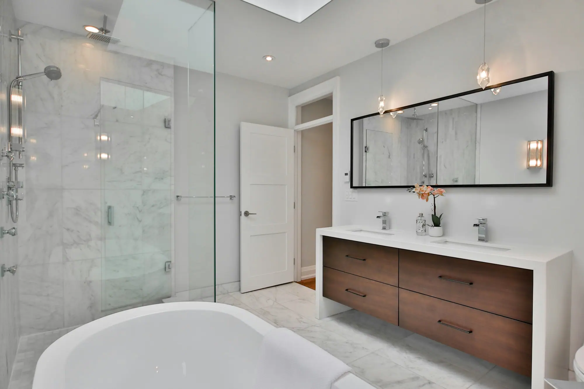 Salle de bain rénovée avec douche à l'italienne vitrée et double vasque sur meuble en bois